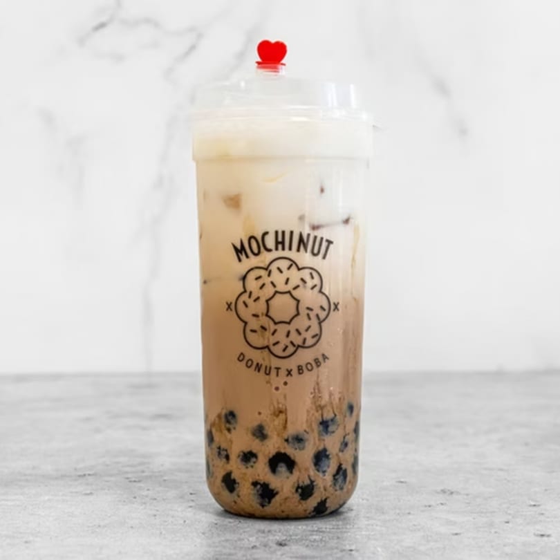 A MochiNut boba tea with a red heart stopper, against a white marble background.