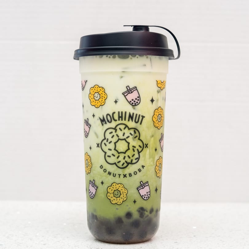 Mochinut matcha boba drink with a black lid, featuring a donut and boba cup design.