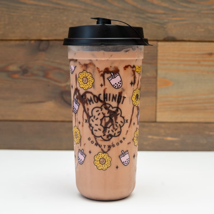 A MochiNut Donut x Boba branded cup with chocolate drizzle and a brown beverage.